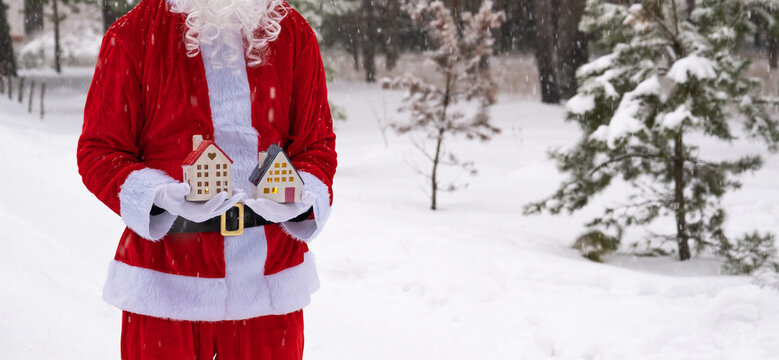 House key with keychain cottage in hands of Santa Claus outdoor in snow. Deal for real estate, purchase, construction, relocation, mortgage. Cozy home. Merry Christmas, new year booking event and hall