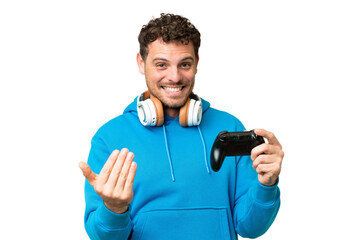 Brazilian man playing with a video game controller over isolated chroma key background inviting to...