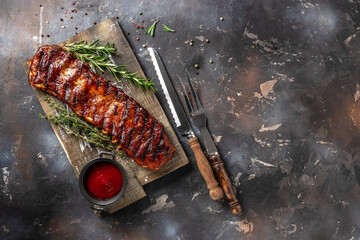 hot grilled spare ribs on cutting board on a dark background. American Spare Ribs in BBQ Sauce. Restaurant menu, dieting, cookbook recipe top view