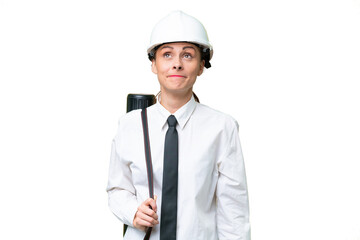 Young architect woman with helmet and holding blueprints over isolated background and looking up