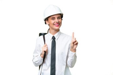 Young architect woman with helmet and holding blueprints over isolated background showing and lifting a finger in sign of the best