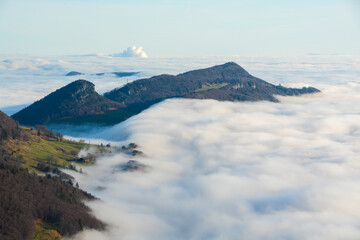 Mountain ridge of solothurn Jura emerging out of a sea of clouds on a sunny winter morning,...