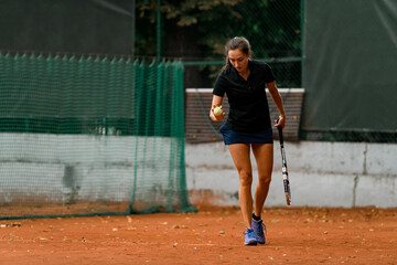 great view of female tennis player holding ball and racket and preparing to serve.