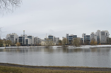 Obraz premium A view from the river bank to multi -storey beautiful buildings in a modern single style
