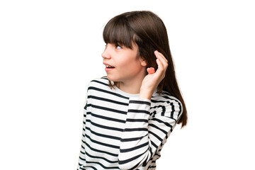 Little caucasian girl over isolated background listening to something by putting hand on the ear