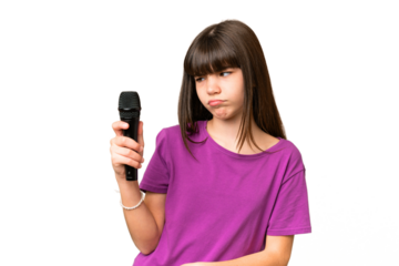 Little singer girl picking up a microphone over isolated background with sad expression