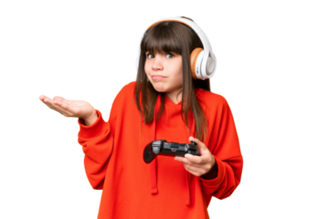 Little caucasian girl playing with a video game controller over isolated background having doubts while raising hands