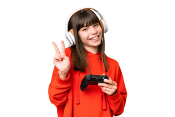 Little caucasian girl playing with a video game controller over isolated background smiling and showing victory sign - obrazy, fototapety, plakaty