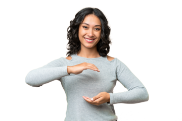 Young Argentinian woman over isolated background holding copyspace imaginary on the palm to insert an ad