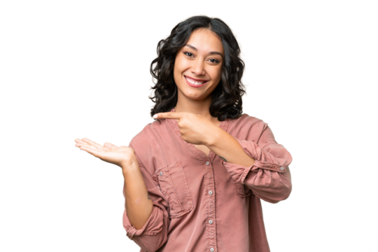 Young Argentinian woman over isolated background holding copyspace imaginary on the palm to insert an ad