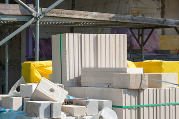 Stapel unterschiedlicher Steine für den Hausbau auf einer Baustelle, Gerüst und Teile des Neubaus...