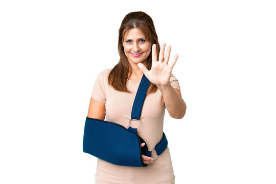 Middle age with broken arm and wearing a sling over isolated background counting five with fingers