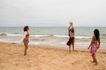 Three young and beautiful women playing boley on the shore of the beach. The women are enjoying the game and their day at the beach in paradise. Holidays and travels.