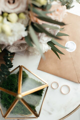 The concept of love and relationships. Wedding invitation. Gold rings on a marble table. The golden casket. The bride's bouquet. Close-up.