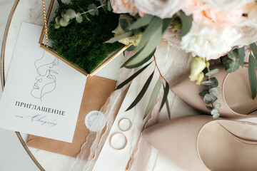 Preparation for the wedding. Wedding invitation. Gold rings on a marble table. The golden casket. The bride's bouquet. Close-up.