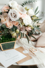 The concept of a future family. Wedding invitation. Gold rings on a marble table. The golden casket. The bride's shoes. The bride's bouquet. Close-up.