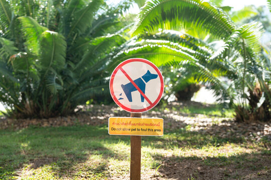 Prohibited to let an animal pets defecating shit in the garden area at public park (English and Thai text language). Sign and symbol for animal object photo, close-up.
