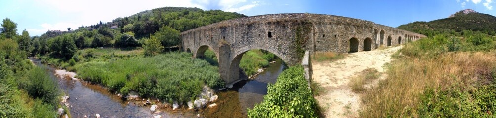 Ancient roman aqueduct passing Agly river and Pic de Vergès mountain near the old village of Ansignan, Occitanie in France - obrazy, fototapety, plakaty