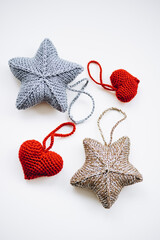 knitted decorations for the Christmas tree. handmade. do it yourself golden and silver stars and red hearts on a white background. place for writing. free space.
