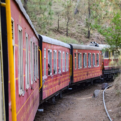 Obraz premium Toy Train moving on mountain slopes, beautiful view, one side mountain, one side valley moving on railway to the hill, among green natural forest. Toy train from Kalka to Shimla in India, Indian Train
