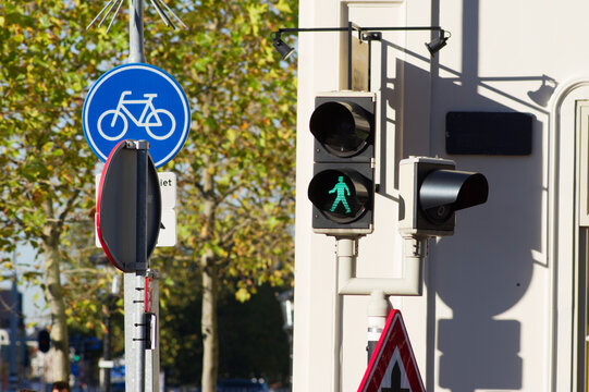 Pedestrian traffic light that turns green with traffic signs and a tree in the background in the Netherlands