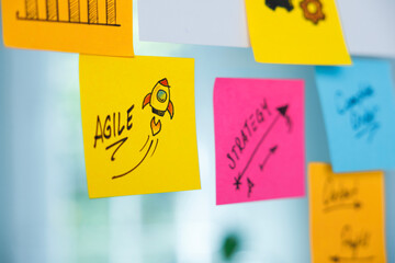The word Agile and rocket symbol on a yellow adhesive note.
