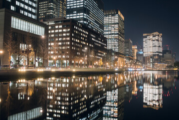 Fototapeta na wymiar 皇居のお濠の水面に映った丸の内〜日比谷のビル群　夜景　Office buildings in Marunouchi District with reflection on Imperial Palace moat at night, Tokyo, Japan