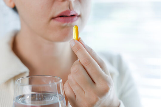 Young woman taking Omega 3 capsule