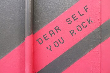 Pink gray wall with text DEAR SELF YOU ROCK, concept of positive self talk to raise self esteem,...