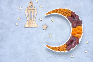Ramadan kareem with dried fruits  arranged in shape of crescent moon. Iftar food concept. Top view, copy space