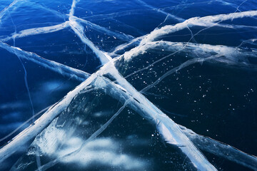 Transparent blue ice with cracks. Lake Baikal in winter. Natural cold background of ice.  