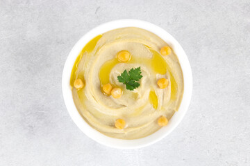 Classic hummus with parsley and olive oil in a plate on a gray background, top view. Arabic, Turkish cuisine.