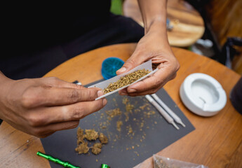 Obraz premium Young man making cigarettes with medical marijuana