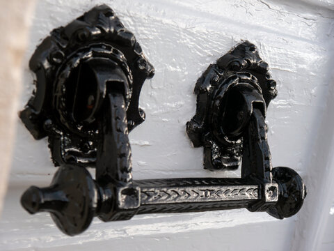 Vintage cast iron door hadle on a wooden panel angle close up view