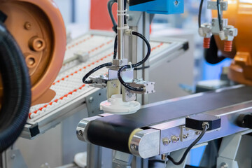 Pick and place robotic arm manipulator moving white plastic detail on conveyor belt at modern robot trade show, exhibition. Manufacturing, industrial, ai, engineering, automated technology concept