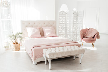 Big comfortable bed with clean linen in room, bed linen pillows blankets pink pastel colors....