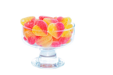 In a glass vase, multi-colored delicious jelly marmalade, isolated on a white background.