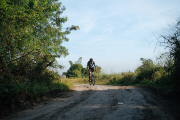 Obraz premium A young bearded cyclist is biking through a dirt path.