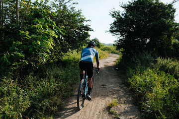 Obraz premium A young bearded cyclist is biking through a dirt path.