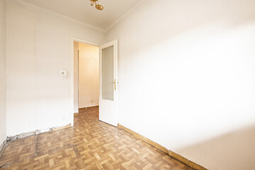 Empty living room with white walls with gotelé, wooden door with glass and without skirting