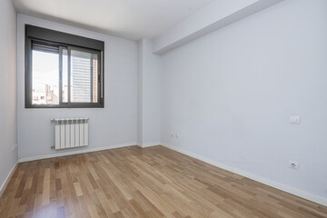 Obraz premium Empty room with blue walls, black anodized aluminum window, white aluminum radiator below and oak wood floors