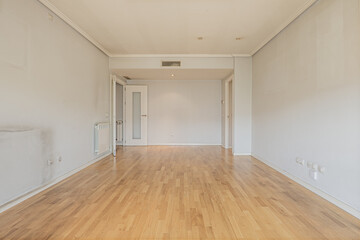 Fototapeta na wymiar Empty room with gray walls, smooth white wooden interior doors, ducted air conditioning in the ceiling, white aluminum radiator below and oak hardwood floors
