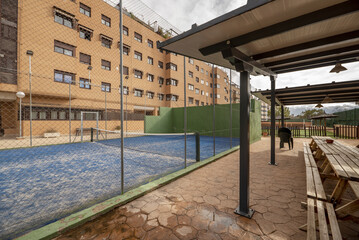 Common areas of an urbanization with a tennis court with gates and gazebos with wooden benches