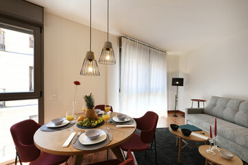 Living room of a vacation rental home with a circular wooden table with a welcome breakfast with juices and fruits