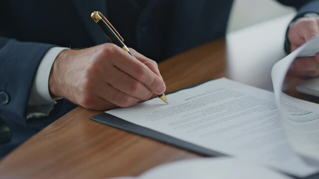 Businessman signing official documents close up. Man putting signature on papers