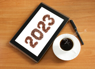 Coffee new year 2023 and tablet pc, coffee beans, cup of coffee isolated on white background, happy new year