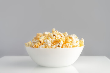 Tasty cheese popcorn in bowl isolated on white background close up. Movies, cinema and entertainment concept.