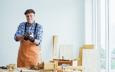 Portrait Caucasian happy old male woodworker or carpenter smiling, wearing shirt with apron,...
