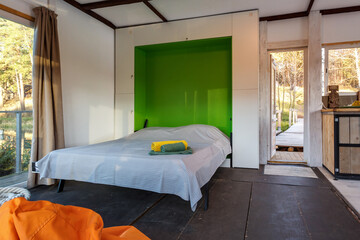 bedroom in a house on the lake with a large bed and a bean bag chair with panoramic windows...