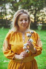 beautiful Ukrainian woman in embroidered dress holds a sprig of cotton